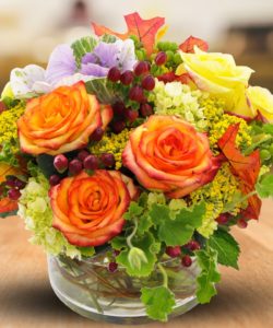 oragne roses with greenery in vase