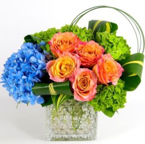 Free Spirit Roses, green and blue Hydrangea, premium greenery in a hobnail glass vessel.