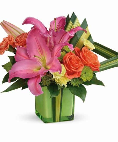 This arrangement will help you daydream about being on Vacation. Beautifully curated in a green glass cube using Hot pink Lilies, orange Roses, and accenting flowers. Using dramatic hala leaves is a tropically-inspired bouquet they receiver will love! 